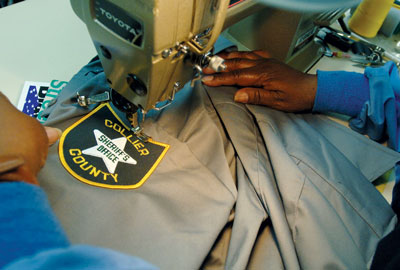 A worker sews a custom patch onto a police uniform